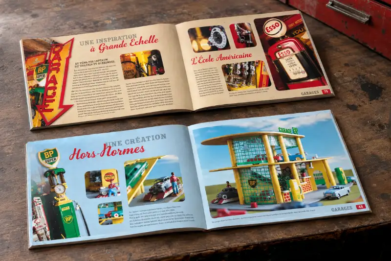 Maquettes ouvertes de deux livres illustrés sur l'univers vintage des stations-services posées sur un établi en bois