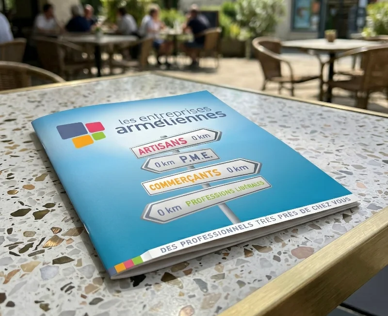 Plaquette imprimée Les Entreprises Arméliennes posée sur une table en terrasse
